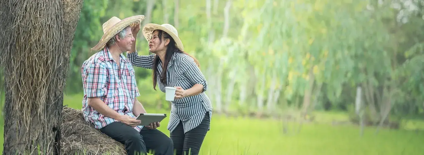 man and woman with hats standing in grass. 